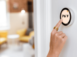 Woman adjusts home thermostat to 76 degrees farenheit