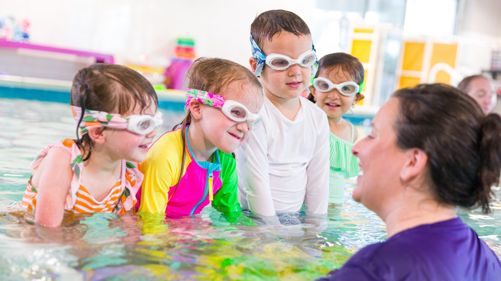 A group of children in a pool taking swimming lessons