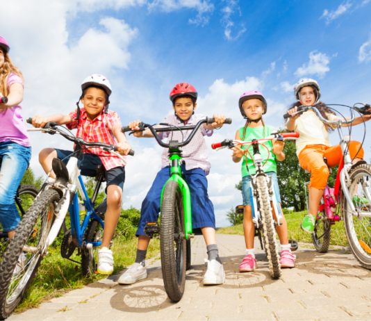 kids wearing bike helmets and riding bicycles on a sunny day