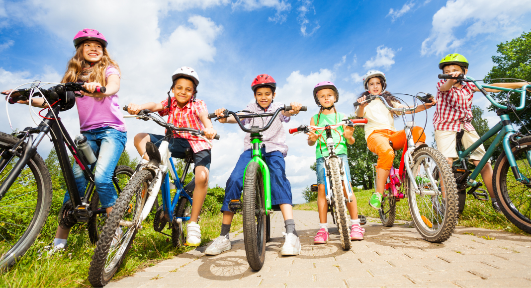 kids wearing bike helmets and riding bicycles on a sunny day